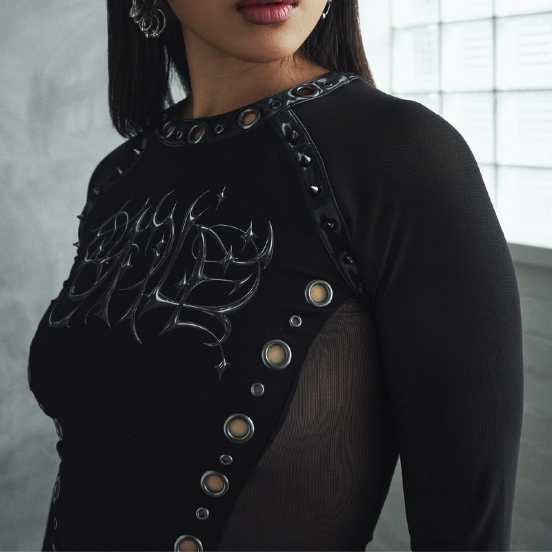 Black outfit with decorative elements worn by a person, against a neutral background