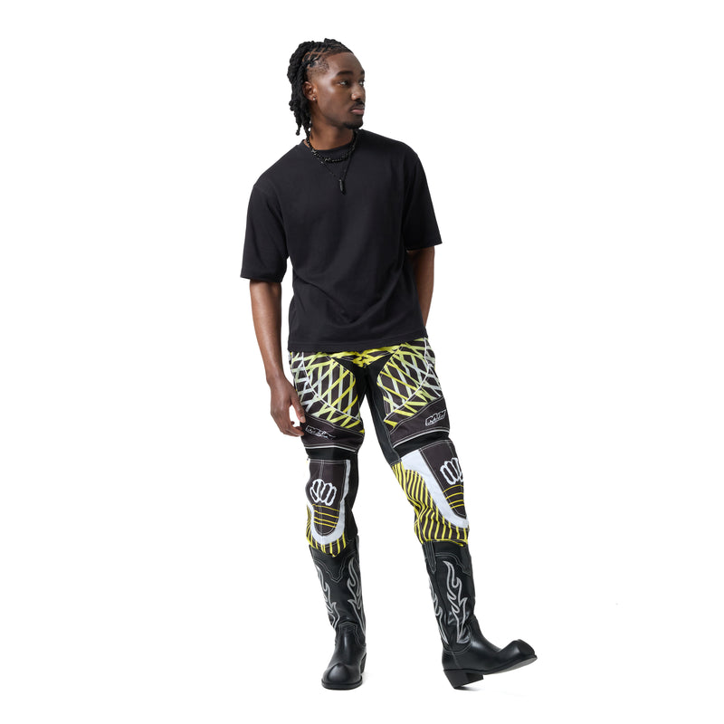 Person wearing black t-shirt, patterned pants, and black boots on a white background