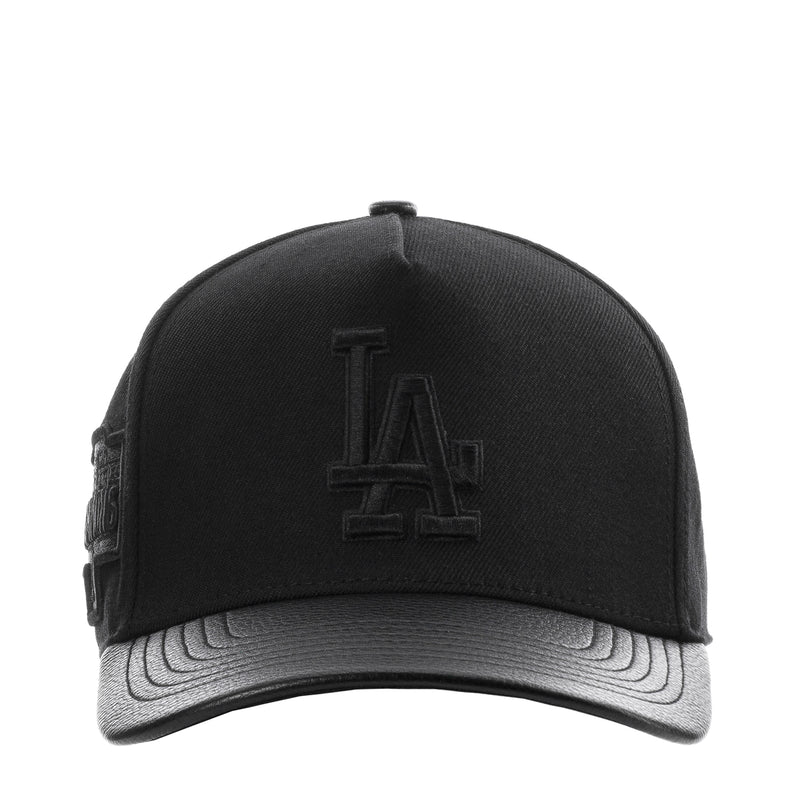 Black pinch-front strapback cap with raised Dodgers 'LA' logo and gray underbrim