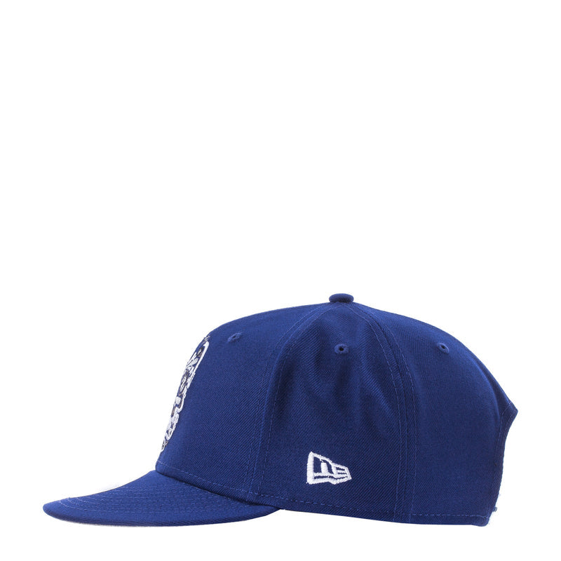 Royal blue baseball cap with white New Era logo and partial skull print