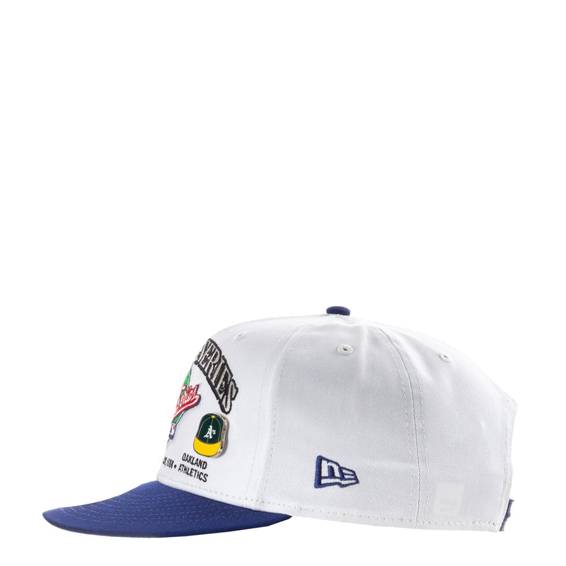 White baseball cap with blue brim, New Era logo, and team patches