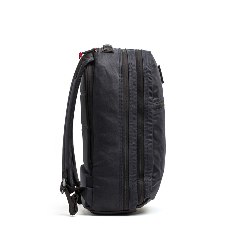 The Double Compartment Bullet Ruck - Heritage Waxed Canvas - 18L stands upright, displayed from the side against a plain white background.