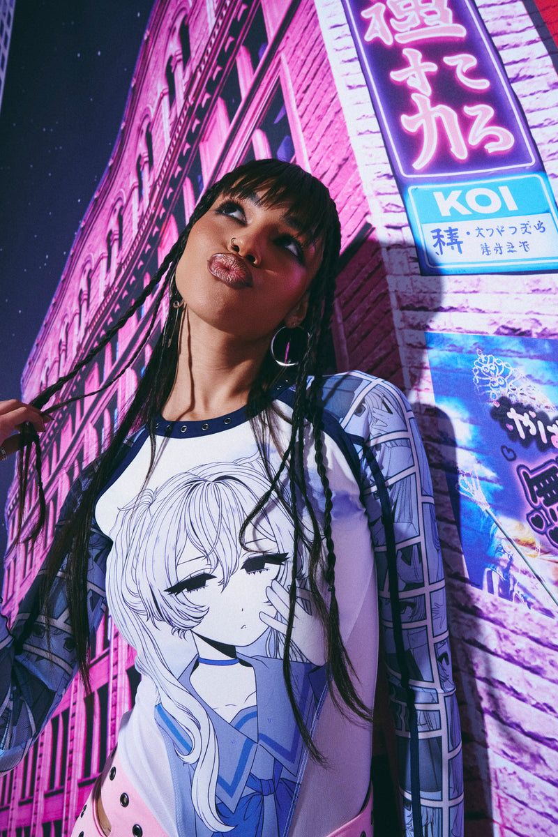Person wearing a shirt with an anime design in front of a neon-lit building.