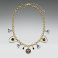 Gold necklace with heart and round pendants on a gray background