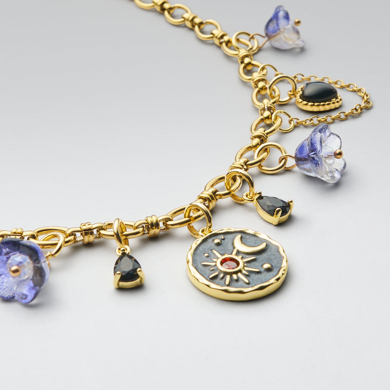 Gold bracelet with various charms on a light gray background