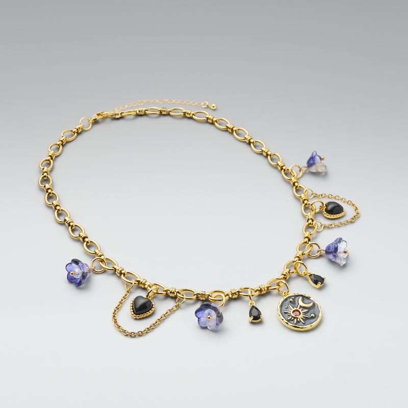 Gold necklace with various charms on a gray background