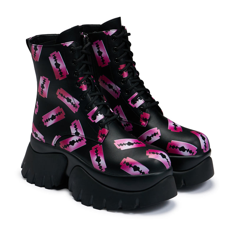 Black platform boots with a pattern of pink razorblade prints, featuring a lace-up front and a chunky sole - 3/4 view
