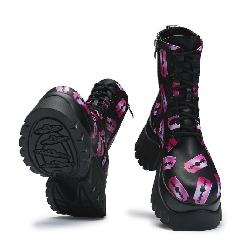 Black platform boots with a pattern of pink razorblade prints, featuring a lace-up front and a chunky sole - front and under view