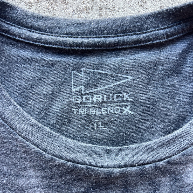 Close-up of the Embrace the Suck Tee - Tri-BlendX in gray, size L, featuring "embrace the suck" and product details printed inside the collar.