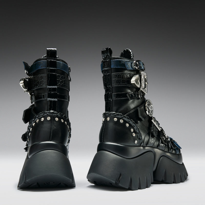 Pair of black high-top boots with metallic accents on a gray background