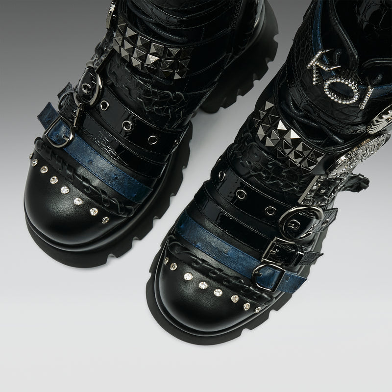 Black studded and buckled boots on a light gray background