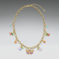 Gold necklace with colorful butterfly and flower charms on a gradient gray background