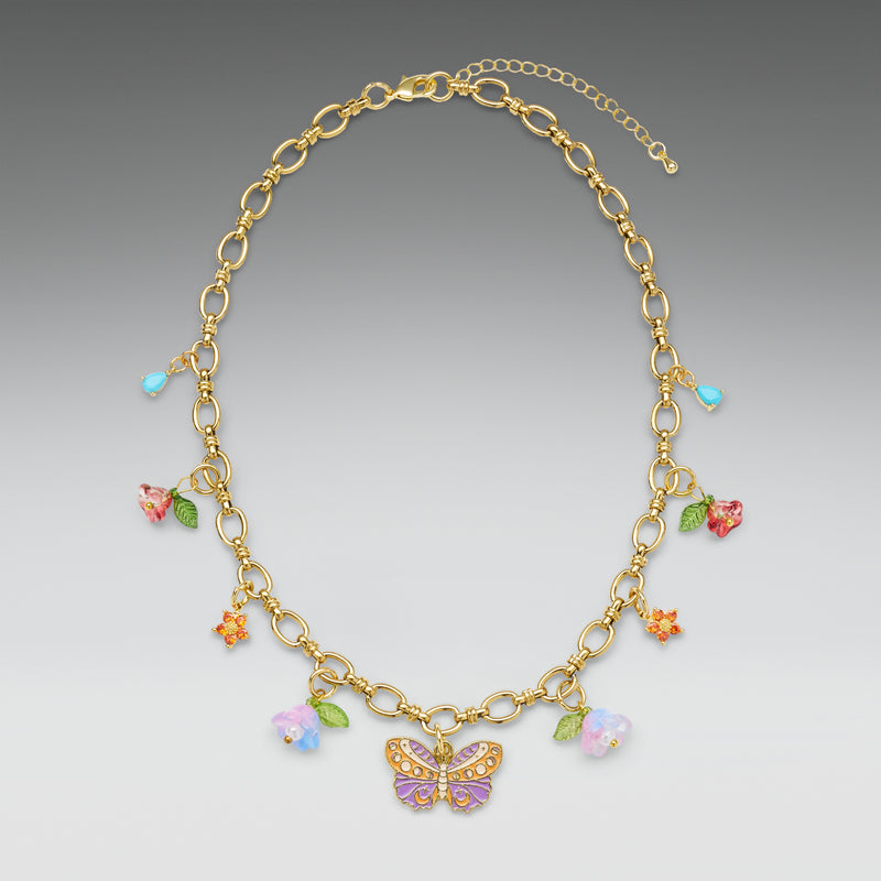 Gold necklace with colorful butterfly and flower charms on a gradient gray background