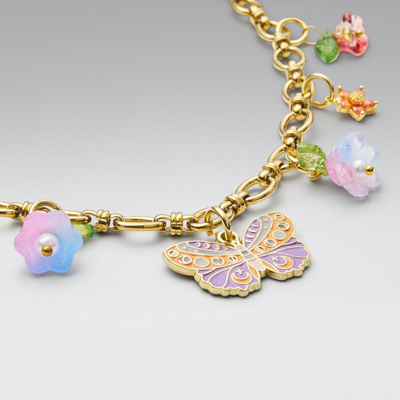 Gold bracelet with colorful charm on a light gray background