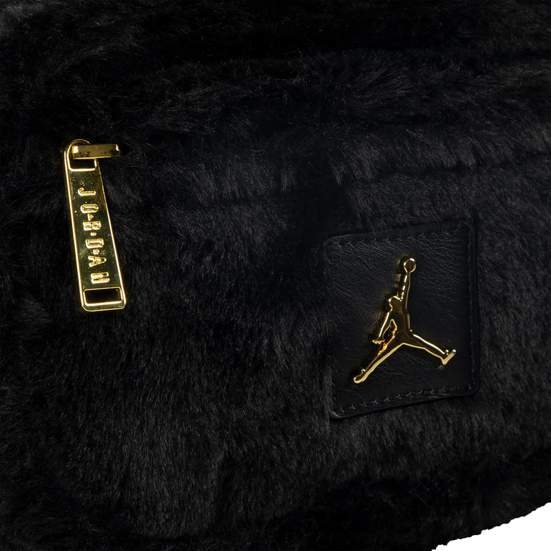 Black faux fur camera bag detail: gold zipper pull, Jumpman logo patch, leather trim