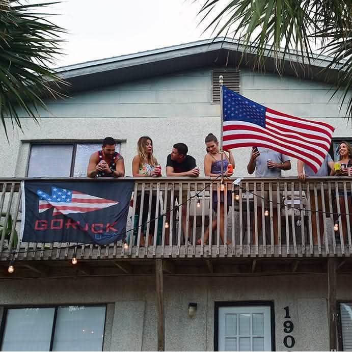 Group on balcony with GORUCK USA flag and large American flag, outdoor gathering scene