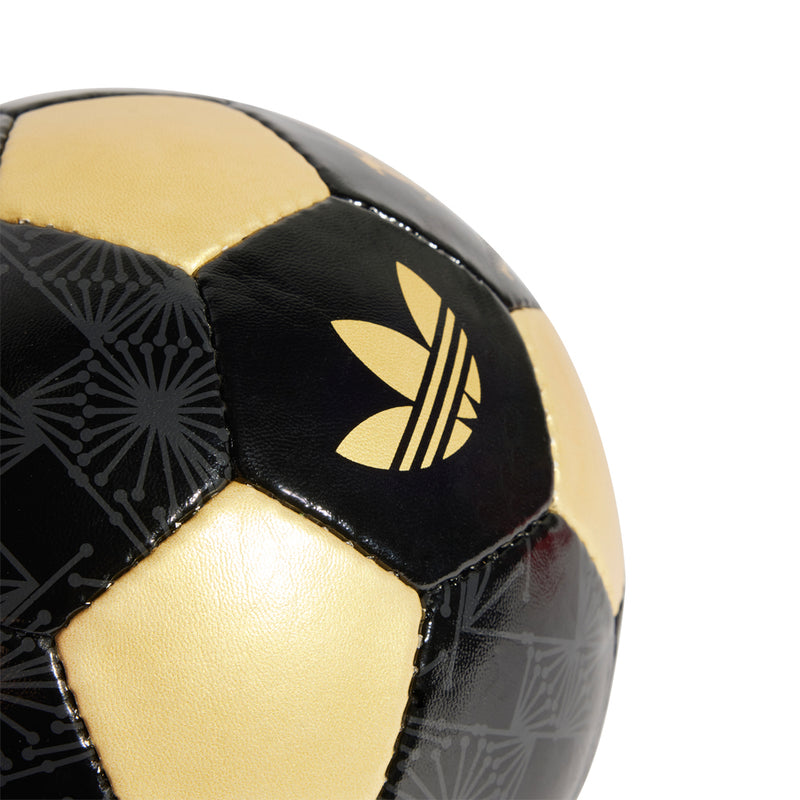 Close-up of black and gold soccer ball panel with trefoil logo