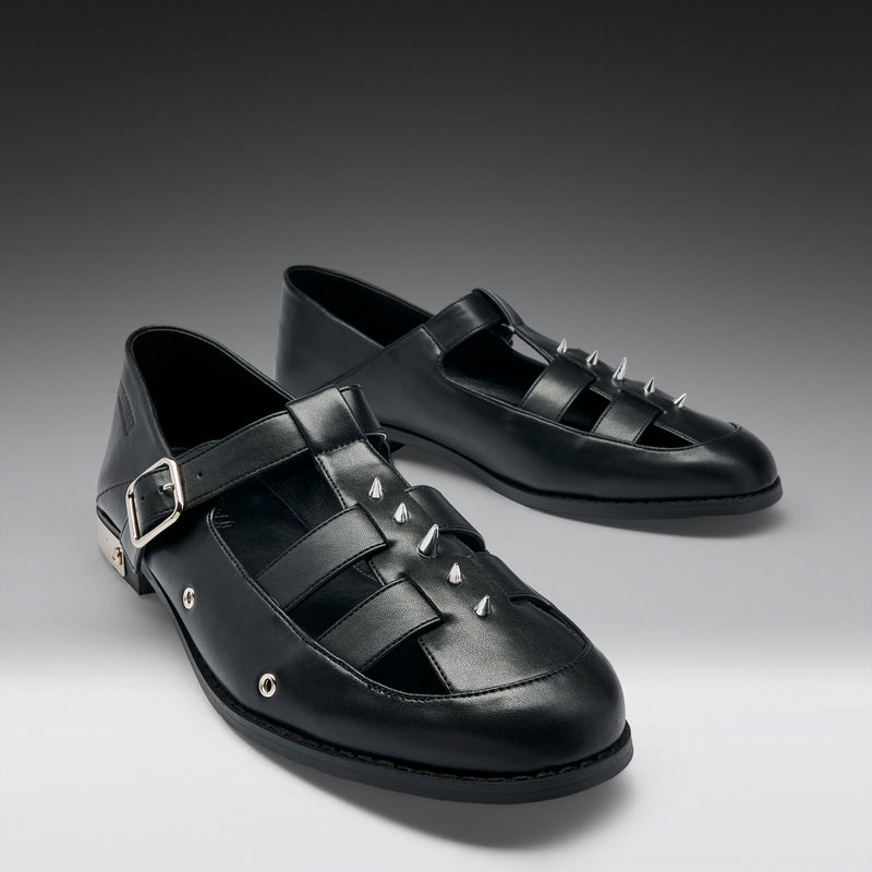 Black leather shoes with buckles and studs on a gray background