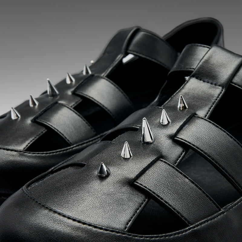 Black leather shoes with silver spikes on a dark background