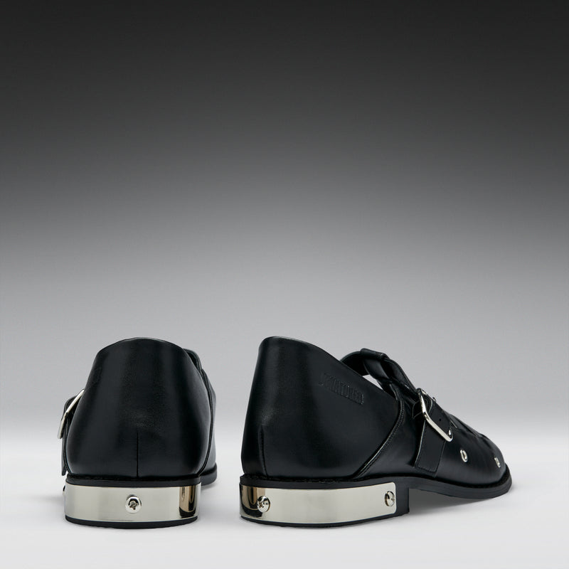 Black leather shoes with silver accents on a gray background