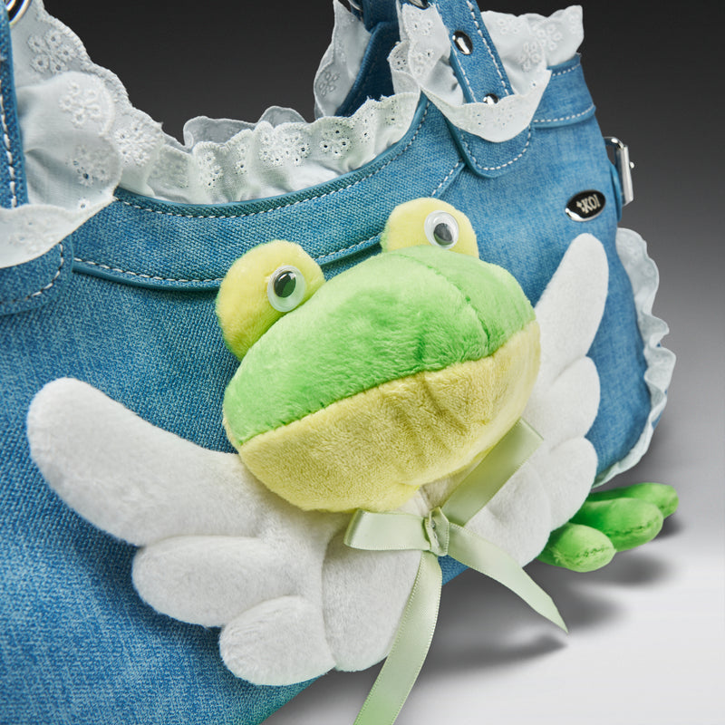 Plush frog toy attached to a denim bag with white lace trim.