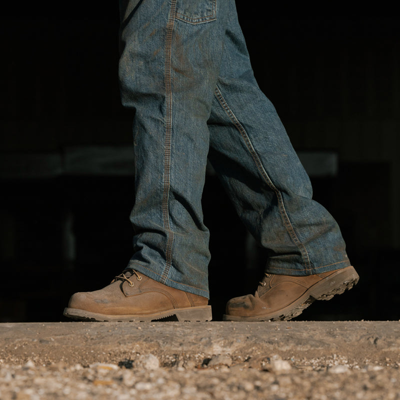 Brown work boots with blue jeans, side view, lace-up closure and thick sole