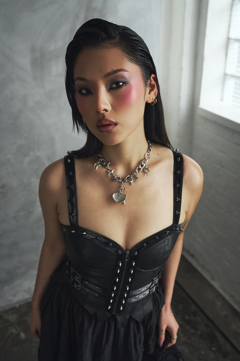 Woman wearing a black corset with a gray wall background