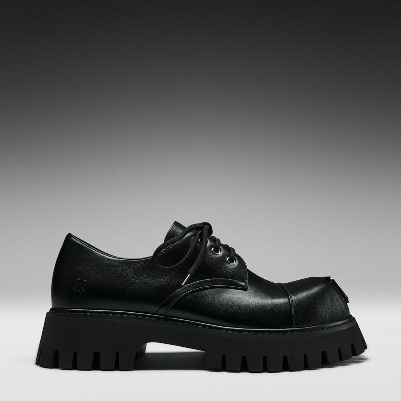Black leather shoe with thick sole on a gray background
