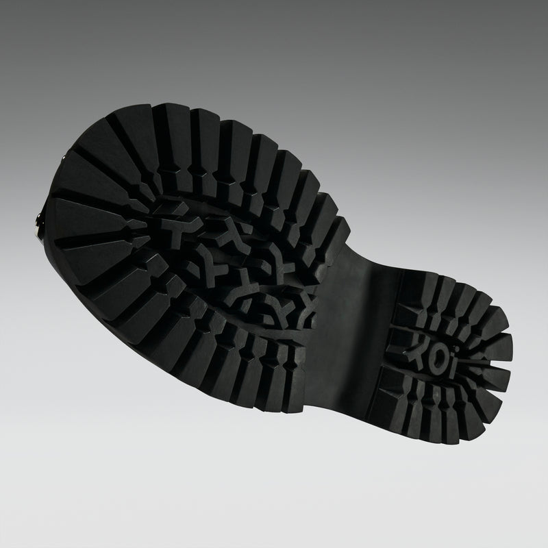 Close-up of a black boot sole with brand logo on a gray background