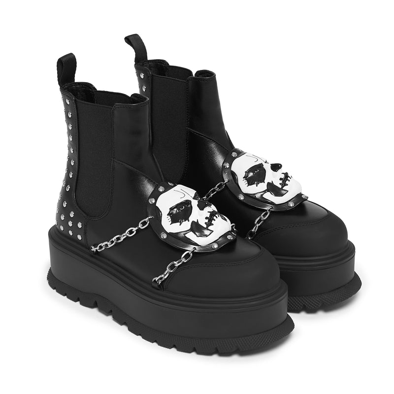 Black platform boots with skull designs and chains on a white background