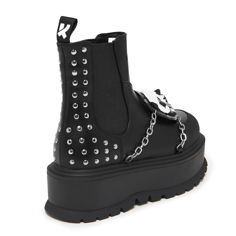 Black platform boot with studs and chain detail on a white background