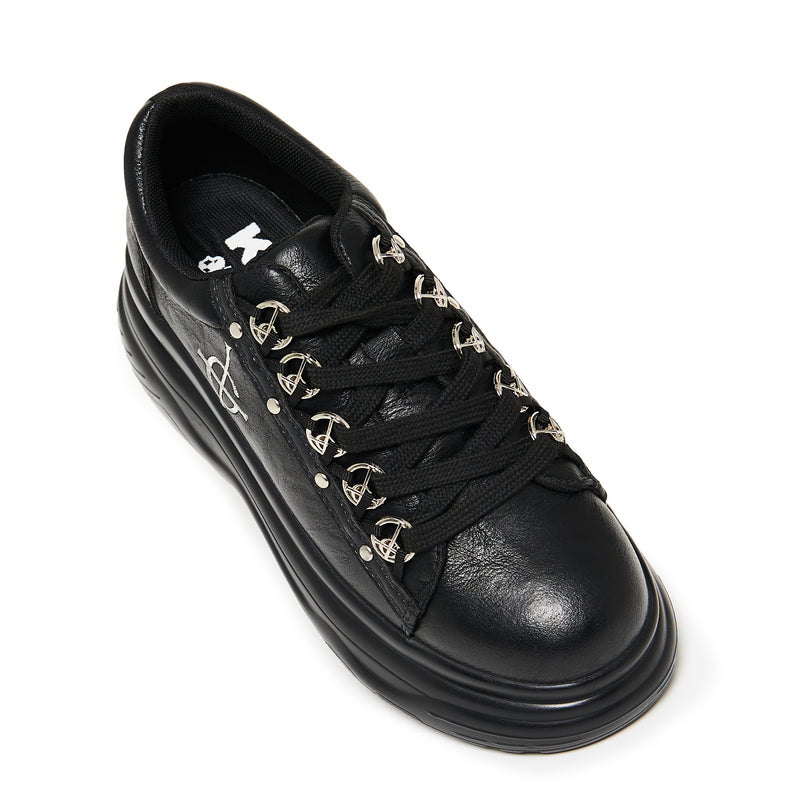 Black sneaker with gold accents on a white background