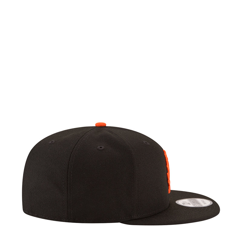 Black baseball cap side profile with orange top button and small orange side detail