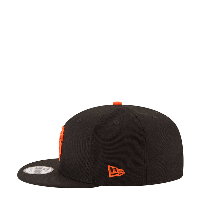 Black baseball cap angled view with orange New Era logo and orange top button