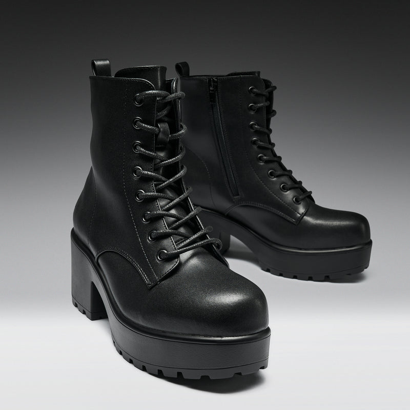 Pair of black leather platform boots on a gradient background