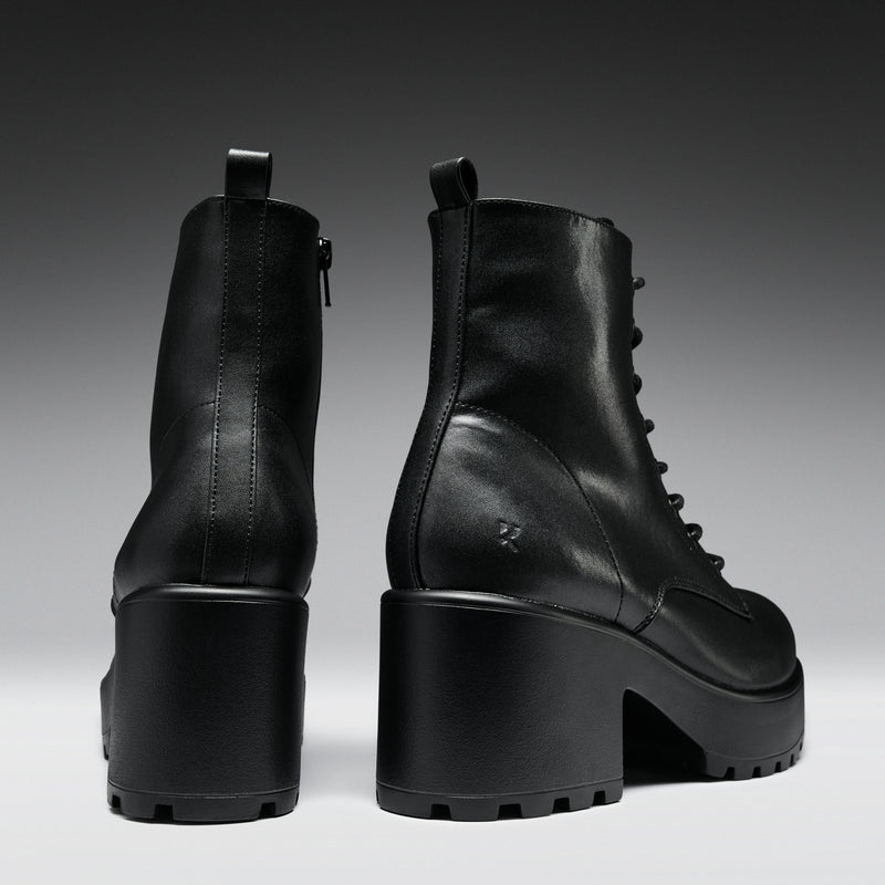 Black leather boots with chunky heels on a gradient background