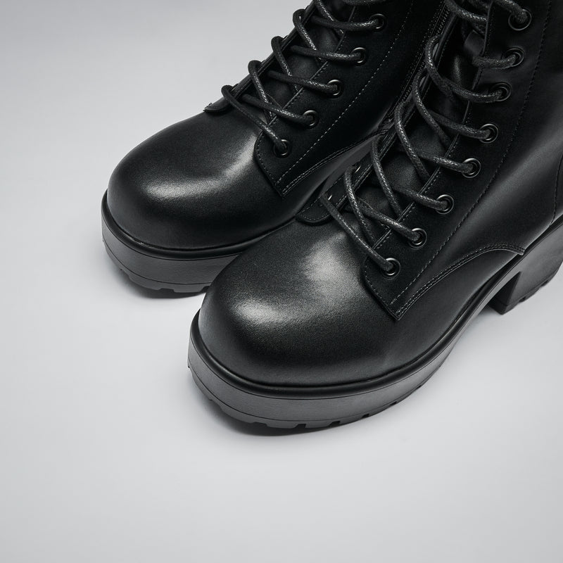 Pair of black leather boots on a light gray background