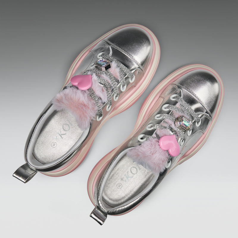 Silver shoes with pink heart details and fluffy elements on a gray background