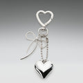 Silver heart-shaped keychain with a bow on a gray background