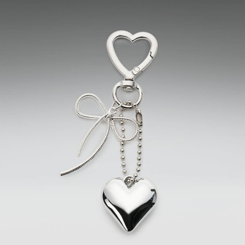 Silver heart-shaped keychain with a bow on a gray background