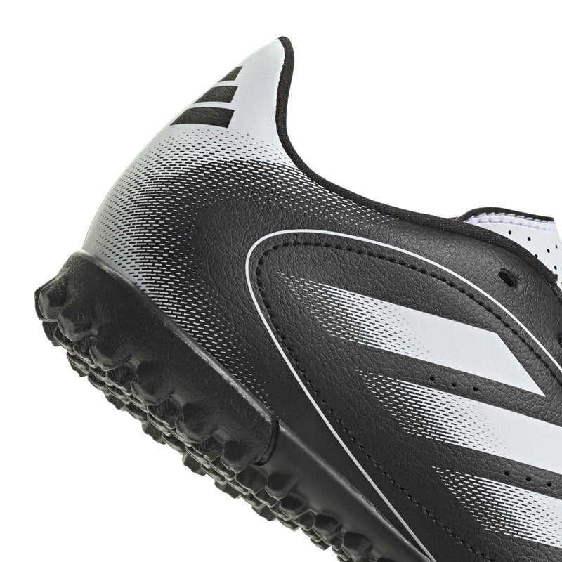 Youth black-and-white turf soccer cleat close-up of textured sole and side stripe