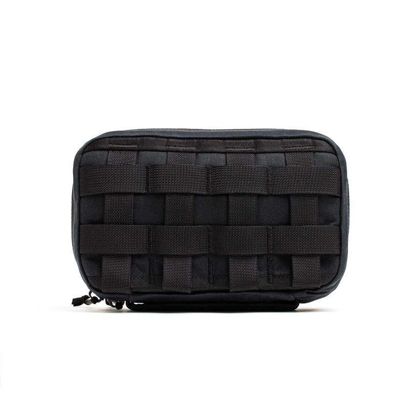 The GR1 Field Pocket - Waxed Canvas is a black rectangular pouch with a woven webbing pattern on the front, made from durable waxed canvas, and shown against a white background.