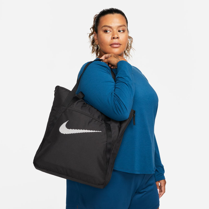 Black gym tote bag with Nike swoosh logo, carried on shoulder with long strap