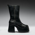 Black leather boot with a platform sole on a gray background