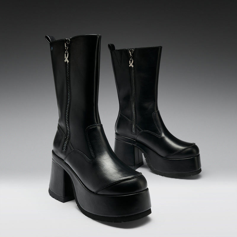 Pair of black platform boots with zippers on a gradient background