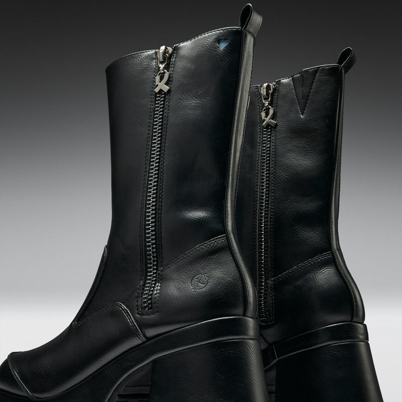 Pair of black leather boots with zippers on a gradient background