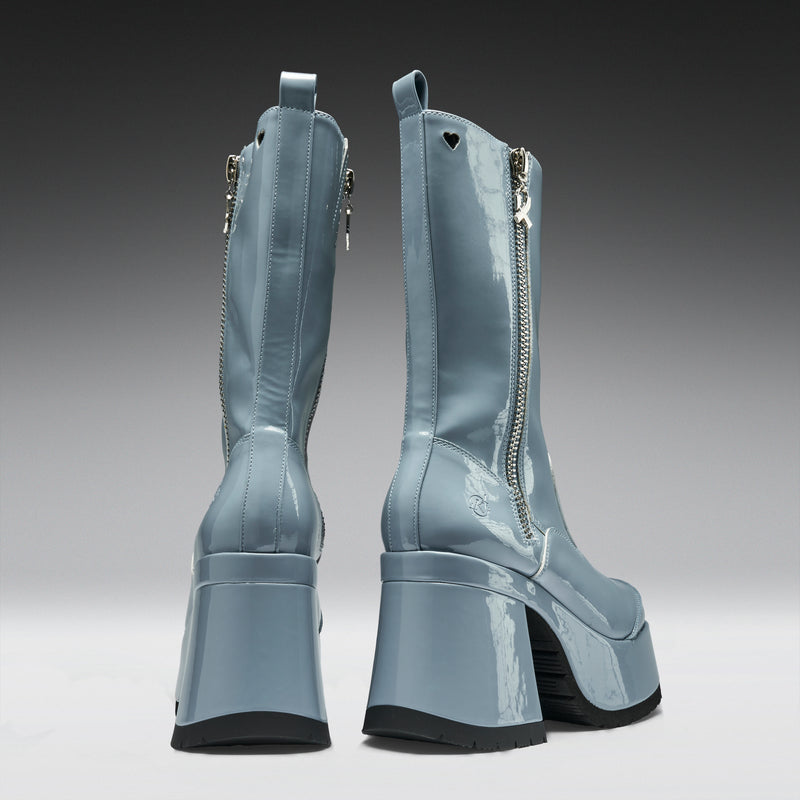 Pair of light blue platform boots with zippers on a gradient background
