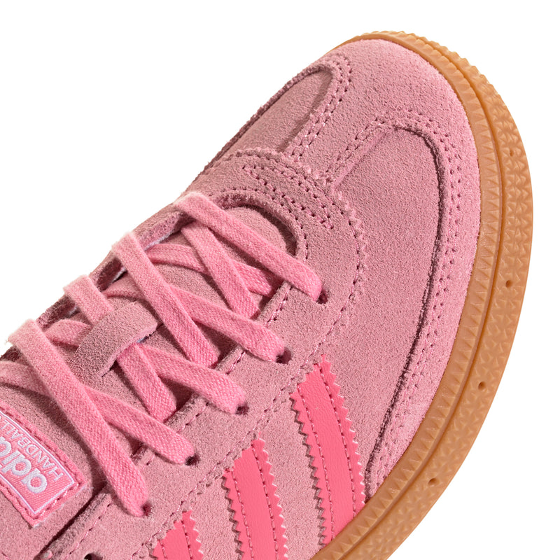 Close-up of kids pink suede sneaker with laces, stitching details, and gum edge