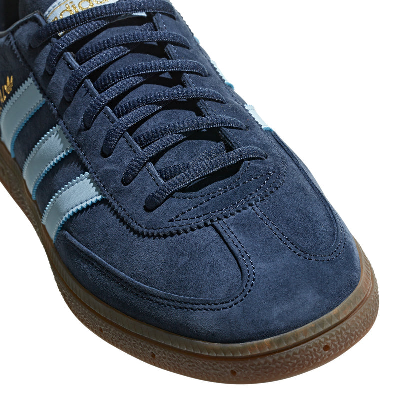 Close-up of navy suede sneakers with blue laces, light blue stripes, gum edge.