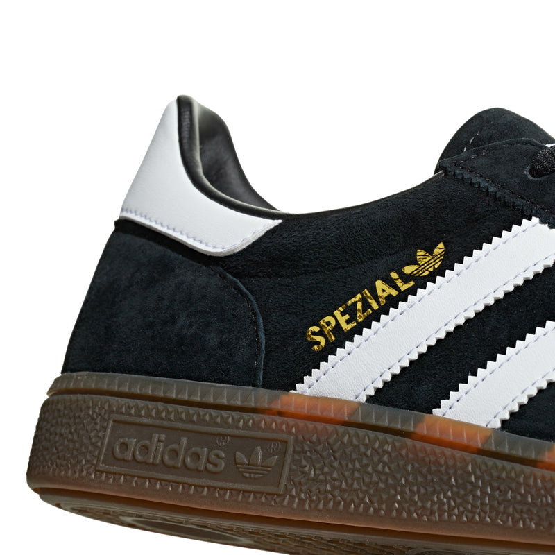 Side close-up of black suede sneaker with gold Spezial text and white stripes